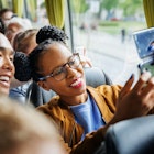 A stylish young couple seize the moment and snap a selfie together as they make their journey on the bus.